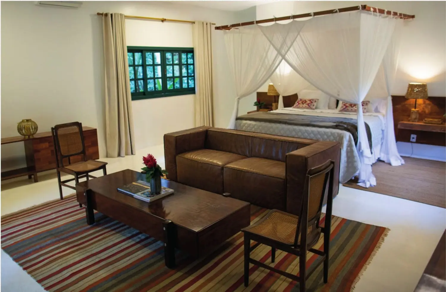 Interior do chalé com cama de dossel e sala de estar